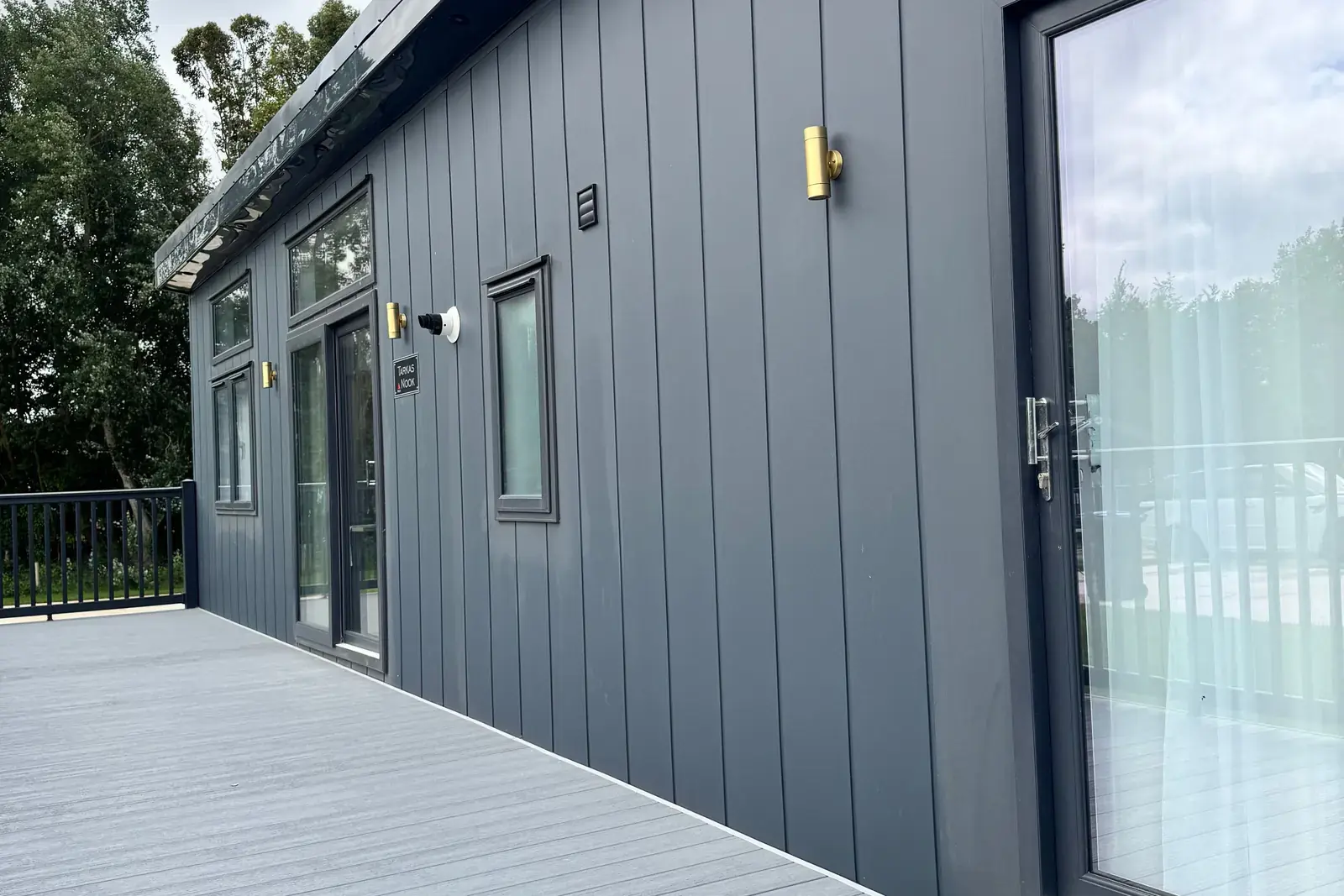 Tarka's Nook from the decking: dark grey cladding, a glazed door and black railings.