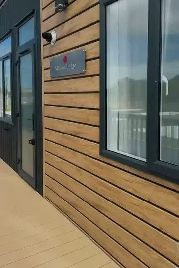 The Marlow Lodge after it arrived: timber-effect cladding, dark window frames, its nameplate and new decking.